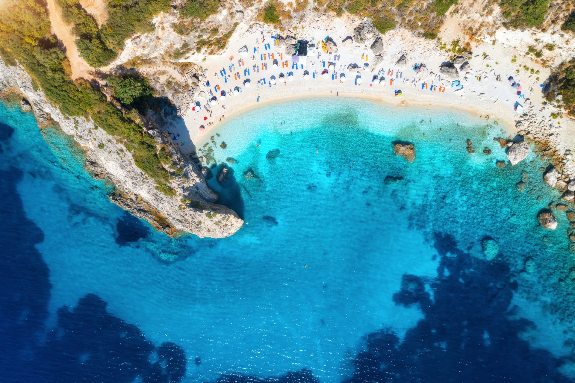 aerial-view-blue-sea-rock-sandy-beach-with-umbrellas-sunrise-summer-porto-katsiki-lefkada-island-greece-beautiful-landscape-with-sea-coast-swimming-people-trees-azure-water-top-view.jpg